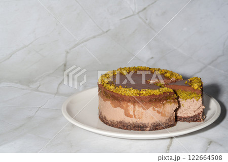 Sliced chocolate Dubai cheesecake with pistachio paste and kataifi dough filling covered in chocolate ganache on white plate. White background copy space. Indulgence, gourmet desserts, art of culinary 122664508