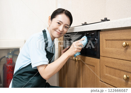 ガスレンジの掃除をするハウスクリーニングの女性 122666087