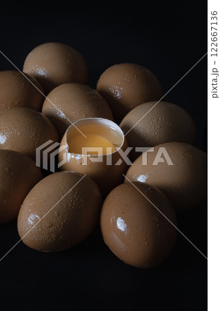 View of Egg yolk in Broken raw chicken eggshell in the among of Fresh chicken egg (Hen egg) on dark background. View of Egg yolk in Broken raw chicken eggshell in the among of Fresh chicken egg (Hen egg) on dark background. 122667136