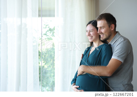 Asian pregnant woman and her husband looking through a window Asian pregnant woman and her husband looking through a window 122667201
