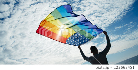 LGBTIQ person waves a rainbow US flag on the sky 122668451