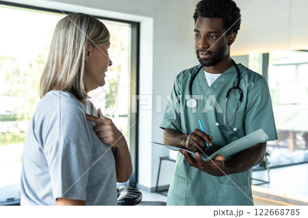 Dark-skinned young male doctor talking to a female patient in a rehabilitation clinic 122668785