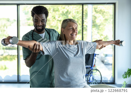 Male dark-skinned doctor working on arms stretching of his female patient 122668791