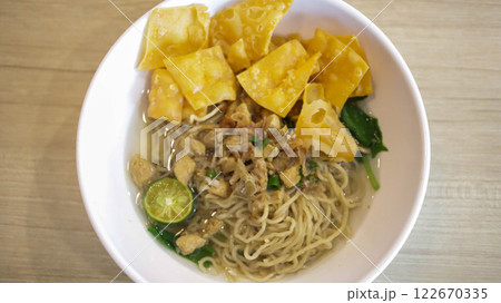 A mouthwatering bowl of Mie Ayam, a popular Indonesian dish yellow wheat noodles with diced chicken, mushrooms, and an array of savory condiments. A delightful blend of Chinese and Indonesian flavors. 122670335