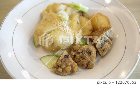 Savor Pempek, savory fishcakes from Palembang, Indonesia, served with sweet and sour kuah cuko sauce. A culinary blend of fish and tapioca, enriched with unique flavors. 122670352