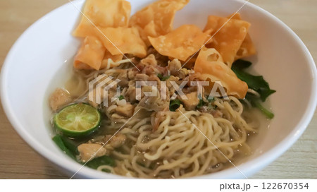 A mouthwatering bowl of Mie Ayam, a popular Indonesian dish yellow wheat noodles with diced chicken, mushrooms, and an array of savory condiments. A delightful blend of Chinese and Indonesian flavors. 122670354