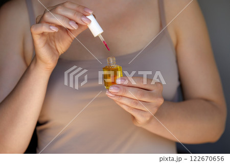 Woman holding bottle of nail polish, close up with copy space. Nail care. Manicure and Hands Spa. Cosmetology, beauty. Skin care 122670656