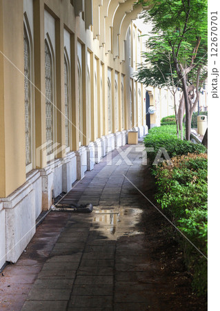 Sidewalk along the house in the shade of trees with a puddle after rain 122670701