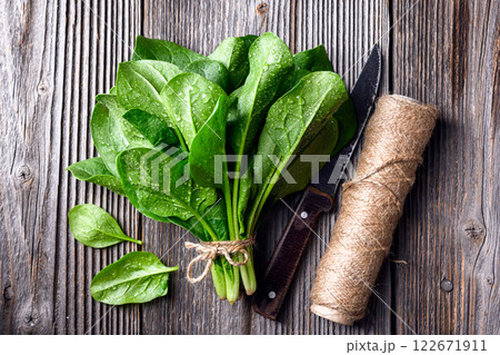 Bunch of fresh green spinach with a skein of twine Bunch of fresh green spinach with a skein of twine 122671911