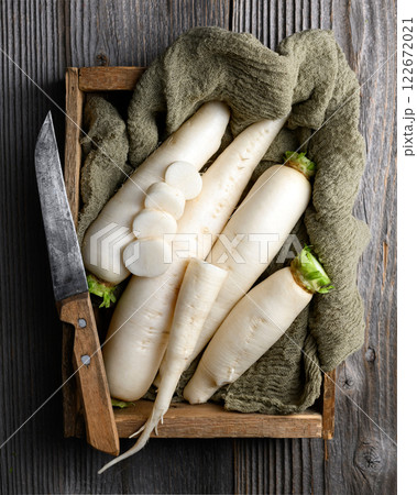White daikon radish roots in wooden box with knife White daikon radish roots in wooden box with knife 122672021