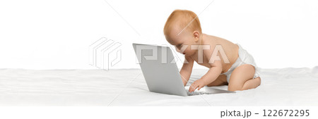 Adorable baby, girl in diaper sitting in bed and typing laptop against white studio background. Early development, education Adorable baby, girl in diaper sitting in bed and typing laptop against white studio background. Early development, education 122672295