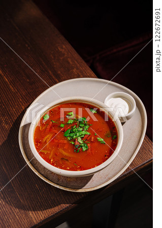 Delicious bowl of spicy tomato soup garnished with fresh herbs served on a wooden table Delicious bowl of spicy tomato soup garnished with fresh herbs served on a wooden table 122672691