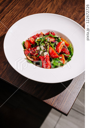 Fresh salad with vibrant vegetables and greens served in a white bowl on a wooden table Fresh salad with vibrant vegetables and greens served in a white bowl on a wooden table 122672726