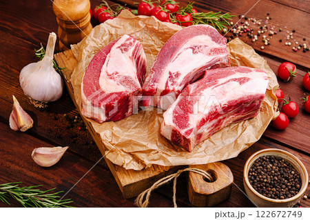 Fresh cuts of meat arranged on a wooden board with herbs and spices for a barbecue preparation 122672749