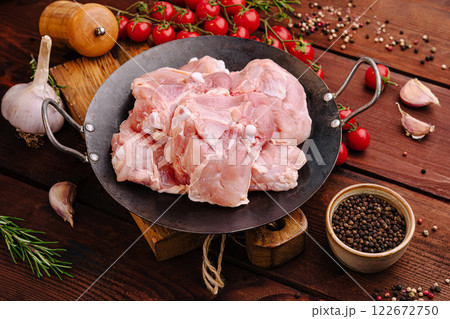 Fresh chicken thighs with spices and vegetables on wooden kitchen table ready for cooking dinner 122672750