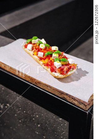 Freshly prepared flatbread topped with vibrant tomatoes, herbs, and cheese on a rustic wooden table Freshly prepared flatbread topped with vibrant tomatoes, herbs, and cheese on a rustic wooden table 122672806