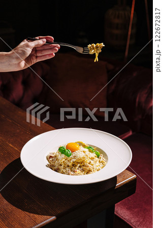 Delicious pasta dish served with fresh ingredients and a vibrant egg yolk in an upscale restaurant setting Delicious pasta dish served with fresh ingredients and a vibrant egg yolk in an upscale restaurant setting 122672817
