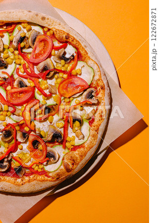 Delicious vegetarian pizza topped with fresh vegetables and vibrant colors on a bright orange background Delicious vegetarian pizza topped with fresh vegetables and vibrant colors on a bright orange background 122672871