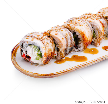 Delicious sushi rolls presented on a white plate drizzled with sauce and sprinkled with sesame seeds 122672881