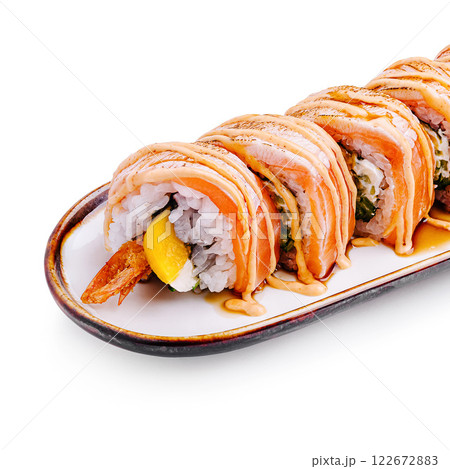 Delicious sushi roll with salmon, shrimp, and avocado served on a white plate with drizzled sauce 122672883