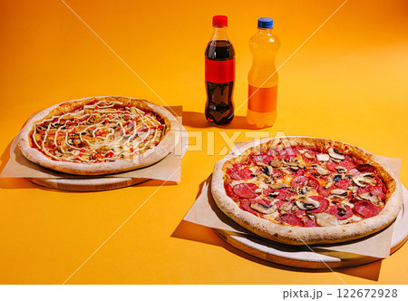 Delicious pizzas and refreshing drinks on vibrant yellow backdrop for a fun dining experience Delicious pizzas and refreshing drinks on vibrant yellow backdrop for a fun dining experience 122672928