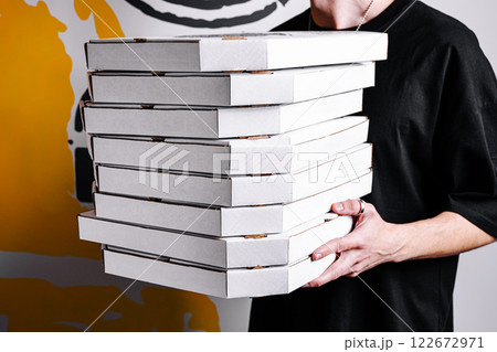 Group of pizza boxes being carried by a person against a colorful background 122672971