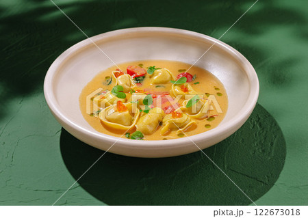 Colorful dish featuring tortellini and vibrant sauce served on a simple plate in a warm, inviting atmosphere Colorful dish featuring tortellini and vibrant sauce served on a simple plate in a warm, inviting atmosphere 122673018