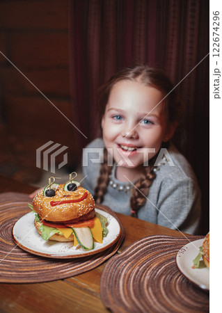 A girl child is sitting in a cafe and is going to A girl child is sitting in a cafe and is going to 122674296