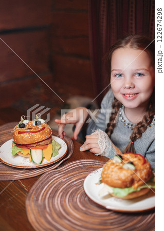 A girl child is sitting in a cafe and is going to 122674298