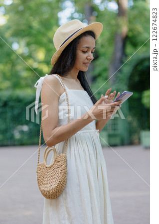 young African American woman in white dress is chatting on smartphone. adorable female model. 122674823
