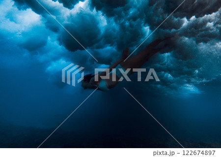 Woman in bikini dive without surf board under ocean wave. Duck dive under crashing wave 122674897