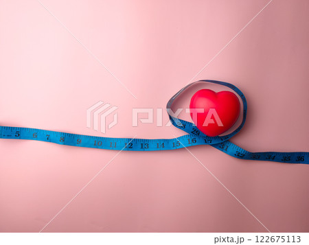 Top view measuring tape with heart shape on a pink background. Medical and health concept. 122675113