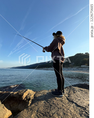 Young happy woman is fishing at sea during spring vacation 122675685