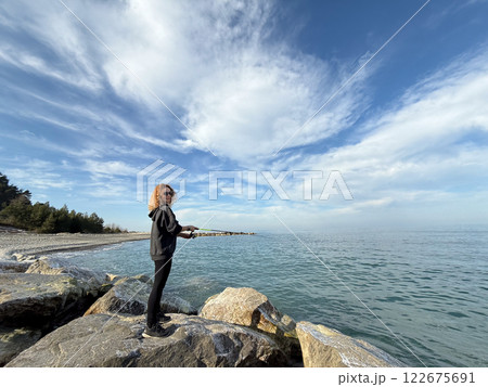 Young happy woman is fishing at sea during spring vacation Young happy woman is fishing at sea during spring vacation 122675691