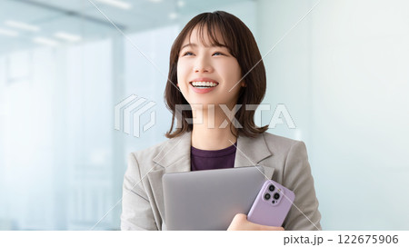 パソコンとスマホを持つ笑顔の若い女性・ビジネスウーマン 122675906