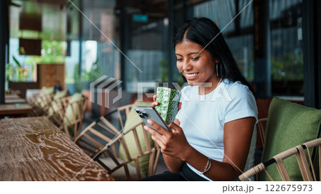 Young Woman Enjoying a Drink and Using Her Phone in a Modern Caf Young Woman Enjoying a Drink and Using Her Phone in a Modern Caf 122675973