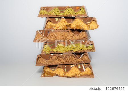 Stack of Trend Dubai chocolate with pistachio, peanut butter, caramel, chocolate spread and kataifi dough. Different flavours. Traditional confectionery. Stack of Trend Dubai chocolate with pistachio, peanut butter, caramel, chocolate spread and kataifi dough. Different flavours. Traditional confectionery. 122676525