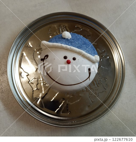 a smiling snowman gingerbread cookie resting on a metallic surface, creating a delightful contrast between the warmth of the festive treat and the coolness of the metal. 122677610
