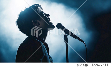 Singer man silhouette on a stage at night. Young man sings in a microphone standing in a spotlight. Pop or rock musical concert. Electronic music. This is AI-generated item  122677611