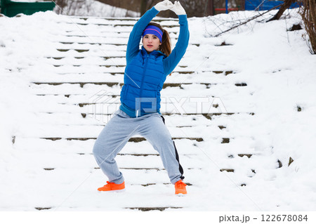 Woman wearing sportswear exercising outside during winter Woman wearing sportswear exercising outside during winter 122678084