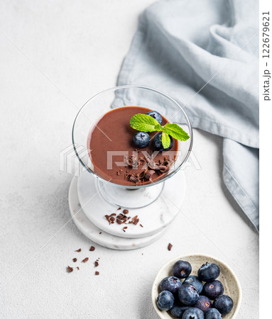 Chocolate pudding in a glass with fresh blueberries and mint on a light background Chocolate pudding in a glass with fresh blueberries and mint on a light background 122679621