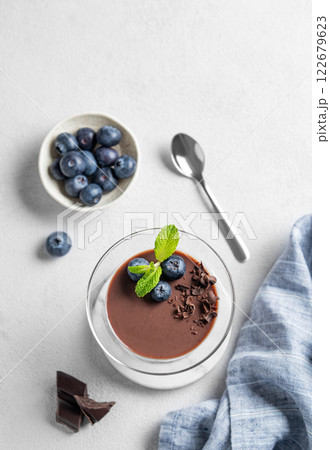 Chocolate pudding in a glass with fresh blueberries and mint on a light background 122679623