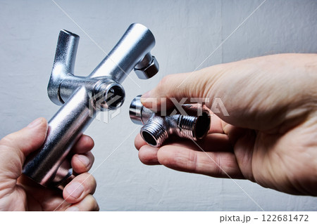 Stainless steel tub and shower faucet set being assembled, showing installation parts in hand. 122681472