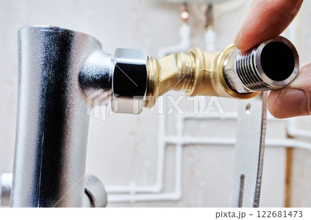 Close-up of hand installing reducer on brass T-fitting, part of plumbing assembly. 122681473