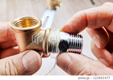 Applying plumbing flax ensures leak proof connection while installing male threaded reducer into brass plumbing fitting. Applying plumbing flax ensures leak proof connection while installing male threaded reducer into brass plumbing fitting. 122681477