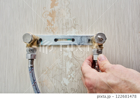 Flexible water hoses are connected to wall mount for bathroom faucet and outlet is closed with pipe plugs. 122681478