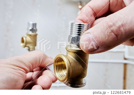 Hands assembling plumbing parts with threaded adapter. 122681479