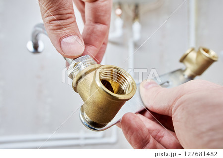 Hands assembling water pipe with metal bracket and connector. 122681482
