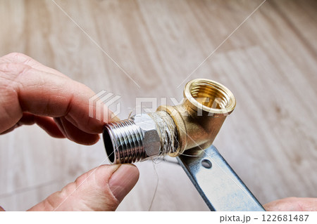 Plumbing flax and sealing paste are applied to male-threaded pipe adapter to ensure a secure and leak-proof connection during plumbing installation. 122681487