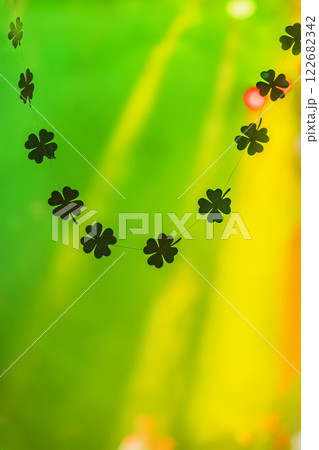 String of black clover decorations against a bright green and yellow illuminated background. Concept of St. Patrick Day celebration and lucky symbols String of black clover decorations against a bright green and yellow illuminated background. Concept of St. Patrick Day celebration and lucky symbols 122682342